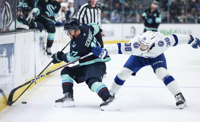 Tampa Bay Lightning left wing Brandon Hagel reaches past Seattle Kraken center Jaden Schwartz during an NHL hockey game Saturday, Dec. 14, 2024, in Seattle. (AP Photo/Maddy Grassy)