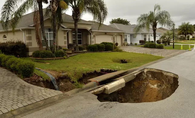 FILE - A sinkhole is shown after opening in the road at the intersection of McAlpin Street and McLawren Terrace in The Villages, Florida, on Monday, May 21, 2018. (George Horsford/Daily Sun via AP, File)