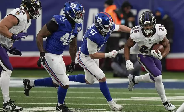 Baltimore Ravens running back Rasheen Ali (26) carries the ball against New York Giants linebacker Micah McFadden (41) and linebacker Tomon Fox (45) during the fourth quarter of an NFL football game, Sunday, Dec. 15, 2024, in East Rutherford, N.J. (AP Photo/Frank Franklin II)