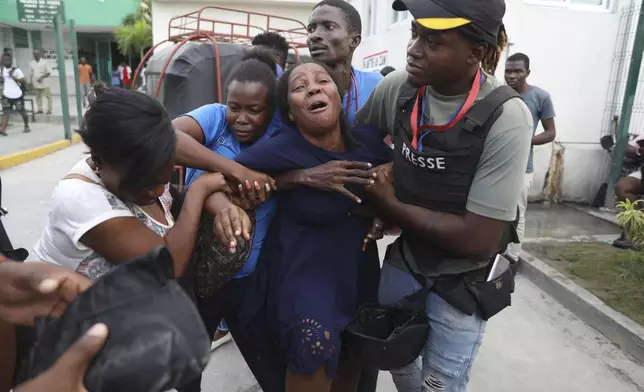 The wife of a journalist, who was shot during an armed gang attack on the General Hospital, cries as an ambulance arrives with his body, at a different hospital in Port-au-Prince, Haiti, Tuesday, Dec. 24, 2024. (AP Photo/Odelyn Joseph)