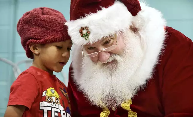 Zane Castello, 6, whispers his Christmas wish to Santa Claus during the Winter Day Camp holiday party at the Greater Johnstown Community YMCA in Johnstown, Pa. on Monday, Dec. 23, 2024. (Thomas Slusser/The Tribune-Democrat via AP)