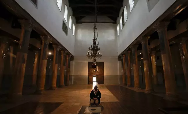 A worshipper prays in the Church of the Nativity, traditionally believed to be the birthplace of Jesus, on Christmas day, in the West Bank city of Bethlehem, Wednesday, Dec. 25, 2024. (AP Photo/Matias Delacroix)