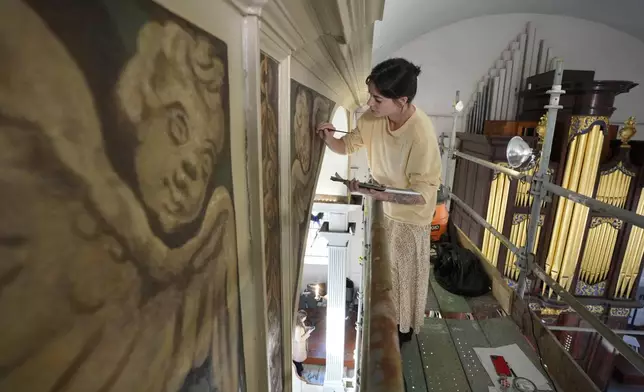 Conservator Corrine Long, of Dover, N.H., restores nearly 300-year-old painted angels on walls of Old North Church, Wednesday, Dec. 18, 2024, in Boston. (AP Photo/Steven Senne)