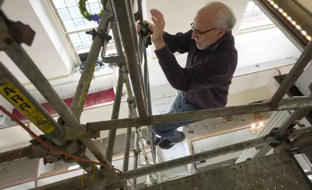 Conservator Gianfranco Pocobene, of Malden, Mass., climbs down scaffolding after working to restore nearly 300-year-old painted angels on the walls of Old North Church, Wednesday, Dec. 18, 2024, in Boston. (AP Photo/Steven Senne)