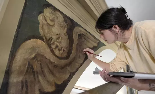 Conservator Corrine Long, of Dover, N.H., restores nearly 300-year-old painted angels on walls of Old North Church, Wednesday, Dec. 18, 2024, in Boston. (AP Photo/Steven Senne)