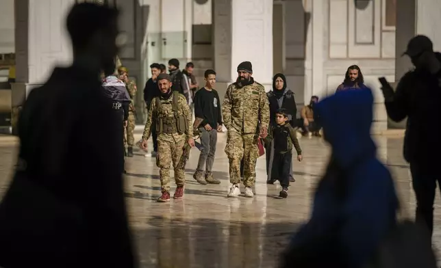 Syrian fighters on military uniform arrive at the Umayyad mosque for Friday prayers in Damascus, Syria, Friday, Dec. 13, 2024. (AP Photo/Leo Correa)