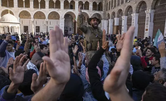 Syrians fighters and civilians chant slogans as they gather for Friday prayers at the Umayyad mosque in Damascus, Syria, Friday, Dec. 13, 2024. (AP Photo/Leo Correa)