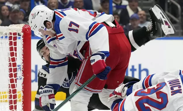 New York Rangers defenseman Will Borgen (17) dumps Tampa Bay Lightning left wing Nick Paul during the second period of an NHL hockey game Saturday, Dec. 28, 2024, in Tampa, Fla. (AP Photo/Chris O'Meara)