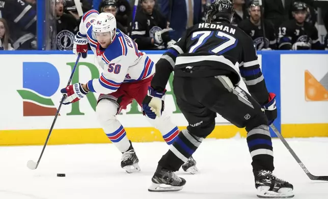 New York Rangers left wing Will Cuylle (50) moves the puck around Tampa Bay Lightning defenseman Victor Hedman (77) during the first period of an NHL hockey game Saturday, Dec. 28, 2024, in Tampa, Fla. (AP Photo/Chris O'Meara)