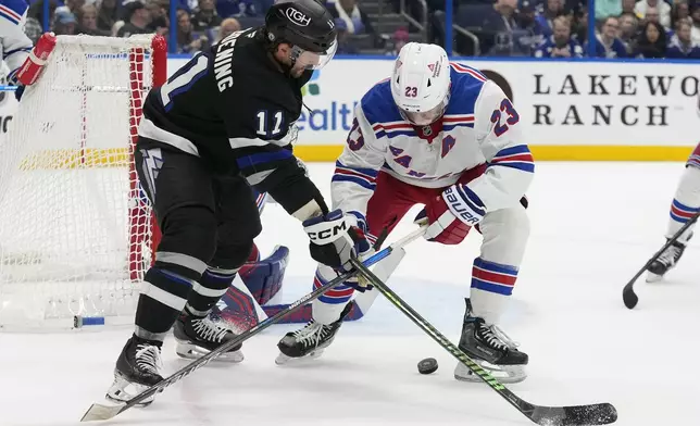 Tampa Bay Lightning center Luke Glendening (11) and New York Rangers defenseman Adam Fox (23) battle for the puck during the second period of an NHL hockey game Saturday, Dec. 28, 2024, in Tampa, Fla. (AP Photo/Chris O'Meara)