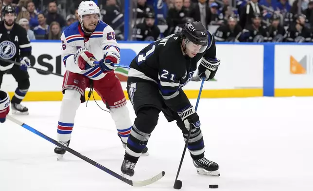 Tampa Bay Lightning center Brayden Point (21) controls the puck in front of New York Rangers defenseman Ryan Lindgren (55) during the second period of an NHL hockey game Saturday, Dec. 28, 2024, in Tampa, Fla. (AP Photo/Chris O'Meara)