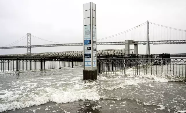 Water from the San Francisco Bay spills onto the Embarcadero in San Francisco on Saturday, Dec. 14, 2024, as a result of high tides and storm-driven waves. (AP Photo/Noah Berger)