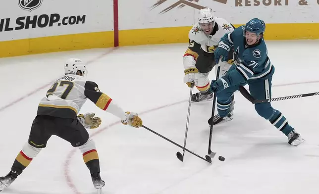 San Jose Sharks center Macklin Celebrini (71) moves the puck while being defended by Vegas Golden Knights defensemen Shea Theodore (27) and Brayden McNabb during the second period of an NHL hockey game, Friday, Dec. 27, 2024, in San Jose, Calif. (AP Photo/Godofredo A. Vásquez)