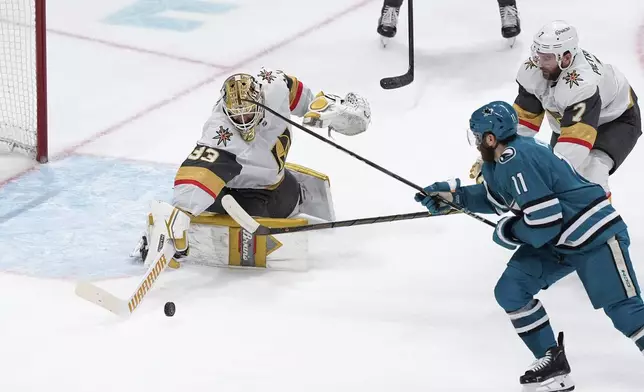 Vegas Golden Knights goaltender Adin Hill, left, stops the shot by San Jose Sharks center Luke Kunin (11) during the second period of an NHL hockey game, Friday, Dec. 27, 2024, in San Jose, Calif. (AP Photo/Godofredo A. Vásquez)