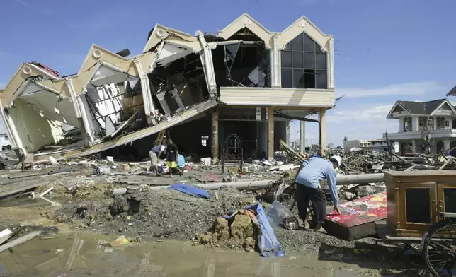 A survivor rummages through the debris at the commercial area of Banda Aceh, the capital of Aceh province in northwest Indonesia, Dec. 31, 2004.(AP Photo/Bullit Marquez, File)