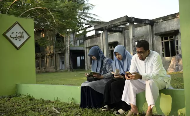 People pray at a mass grave of victims of the 2004 Indian Ocean tsunami in Banda Aceh, Indonesia, Thursday, Dec. 26, 2024. (AP Photo/Reza Saifullah)