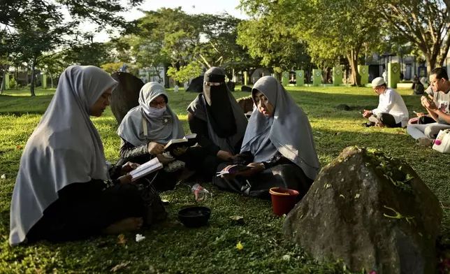 People pray at a mass grave of victims of the 2004 Indian Ocean tsunami in Banda Aceh, Indonesia, Thursday, Dec. 26, 2024. (AP Photo/Reza Saifullah)