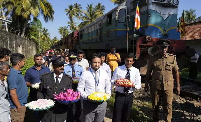 Railway workers and locomotive drivers carry flowers to offer at a memorial built in memory of those who died during 2004 Indian Ocean tsunami as they mark the 20th anniversary in Peraliya, Sri Lanka, Thursday, Dec. 26, 2024. (AP Photo/Eranga Jayawardena)