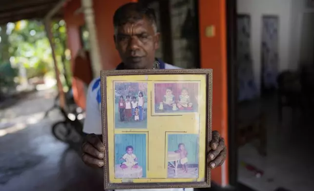 Tsunami survivor Kumudu Priyantha holds photographs of his three daughters and wife who died during 2004 Indian Ocean tsunami during its 20th anniversary in Peraliya, Sri Lanka, Thursday, Dec. 26, 2024. (AP Photo/Eranga Jayawardena)