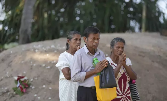 Relatives pray for their dead relatives in 2004 Indian Ocean tsunami, standing by a mass grave during a memorial of the 20th anniversary of the calamity in Peraliya, Sri Lanka, Thursday, Dec. 26, 2024. (AP Photo/Eranga Jayawardena)