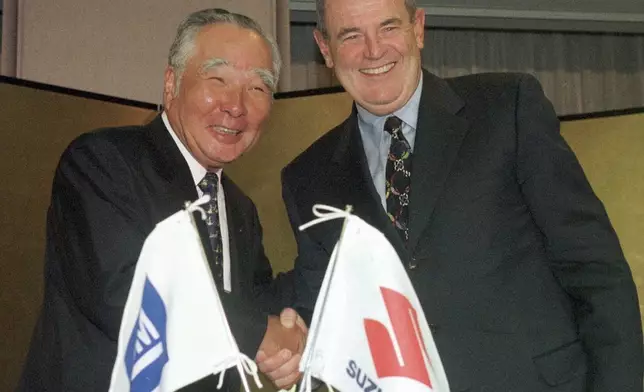 FILE - General Motors Chairman John F. Smith, left, and Osamu Suzuki, president and CEO of Suzuki Motor Corp., smile after announcing the two automakers' agreement to increase coordination of their global manufacturing operations in Tokyo, Sept. 16, 1998. (AP Photo/Katsumi Kasahara, File)