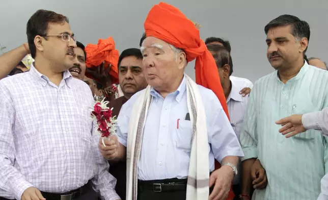 FILE - Suzuki Motor Corp. Chairman and Chief Executive Osamu Suzuki, center, receives a traditional welcome during his visit to the proposed site for Maruti Suzuki India Ltd's (MSIL) manufacturing facility at Hansalpur near Mehsana, about 110 kilometers (70 miles) north of Ahmadabad, India, Aug. 25, 2012. (AP Photo/AJit Solanki, File)