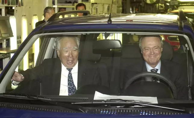 FILE - Osamu Suzuki, head of the Suzuki Motor Corporation, left, sits in the first Suzuki Ignis made in Hungary next to Hungarian Prime Minister Peter Medgyessy just after the production start of the new Suzuki model in Esztergom near Budapest, Hungary, April 10, 2003. (AP Photo/Bela Szandelszky, File)