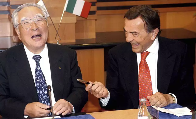 FILE - Chairman and CEO of the Japanese carmaker Suzuki Motor Corp., Osamu Suzuki, left, and President and CEO of Fiat Auto S.p.A. of Italy, Giancarlo Boschetti, share a laugh before they signed an agreement on jointly developing and producing a new sport utility vehicle in a hotel in Budapest, Hungary, April 10, 2003. (Tamas Kovacs/MTI via AP, File)