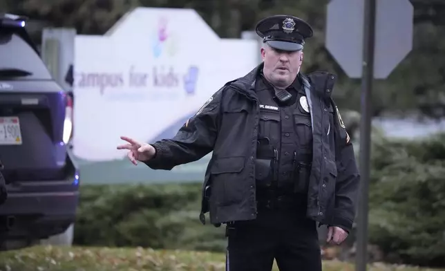 A police officer directs traffic as emergency vehicles are parked outside the Abundant Life Christian School in Madison, Wis., where multiple injuries were reported following a shooting, Monday, Dec. 16, 2024. (AP Photo/Morry Gash)