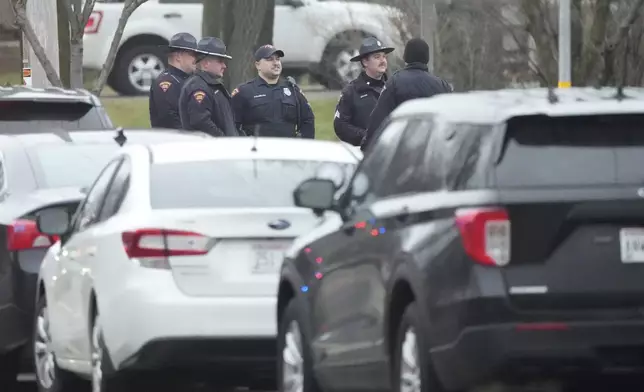 Police gather as emergency vehicles are parked outside the Abundant Life Christian School in Madison, Wis., where multiple injuries were reported following a shooting, Monday, Dec. 16, 2024. (AP Photo/Morry Gash)