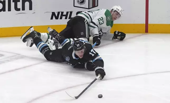 Dallas Stars defenseman Esa Lindell (23) and Utah Hockey Club center Nick Bjugstad (17) battle for the puck during the second period of an NHL hockey game Monday, Dec. 2, 2024, in Salt Lake City. (AP Photo/Rick Bowmer)