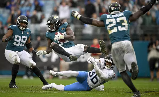 Jacksonville Jaguars linebacker Devin Lloyd, second from left, makes an interception over Tennessee Titans running back Julius Chestnut (36) during the first half of an NFL football game, Sunday, Dec. 29, 2024, in Jacksonville, Fla. (AP Photo/Phelan M. Ebenhack)