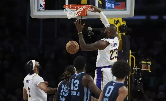 Los Angeles Lakers forward LeBron James (23) dunks the ball as forward Anthony Davis (3), Memphis Grizzlies forward Brandon Clarke (15), forward Jaren Jackson Jr. (13), forward Brandon Clarke (15) and forward Jaylen Wells (0) watch during the first half of an NBA basketball game, Sunday, Dec. 15, 2024, in Los Angeles. (AP Photo/Jessie Alcheh)