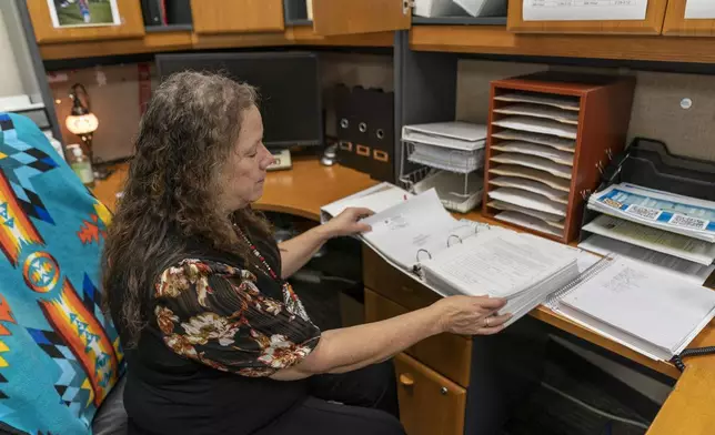 Indian Education Director Hollie Youngbear looks over a binder of info she compiles about her students in her office at Watonga High School on Wednesday, Oct. 2, 2024, in Watonga, Okla. Youngbear and her colleagues work to connect with families in a way that acknowledges the history and needs of Native communities. (AP Photo/Nick Oxford)