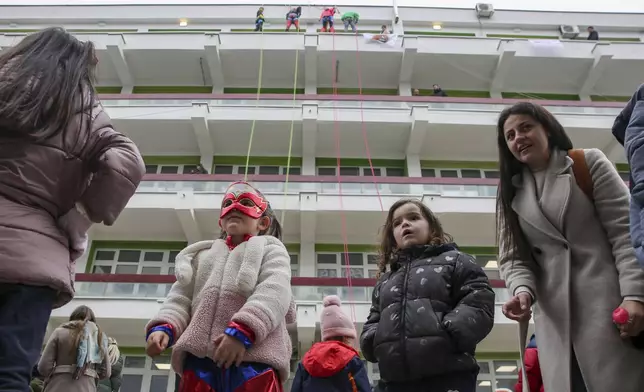 Children dressed as superheroes watch Kosovo alpinists disguised as super-heroes of modern times delivering New Year's gifts to children patients in Pristina hospital on Friday, Dec. 13, 2024. (AP Photo/Visar Kryeziu)