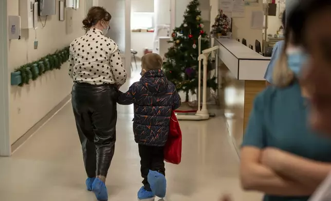 A patient with his mother walks back to his room after Kosovo alpinists disguised as super-heroes brought gifts in Pristina hospital on Friday, Dec. 13, 2024. (AP Photo/Visar Kryeziu)