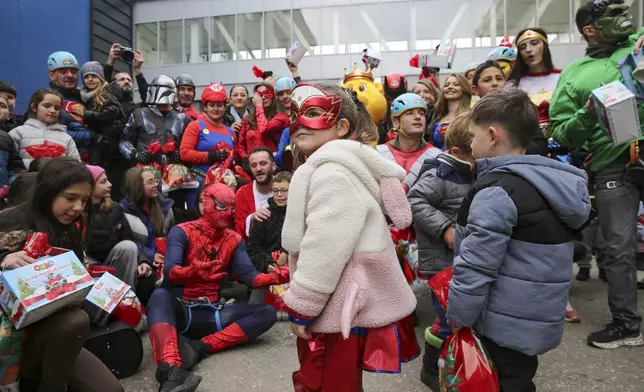 Children dressed as superheroes greet Kosovo alpinists disguised as super-heroes of modern times delivering New Year's gifts to children patients in Pristina hospital on Friday, Dec. 13, 20124. (AP Photo/Visar Kryeziu)