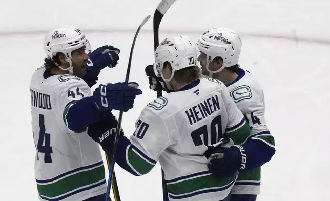 Vancouver Canucks' Danton Heinen (20) celebrates with teammates Kiefer Sherwood (44) and Pius Suter (24) after scoring against the Utah Hockey Club during the second period of an NHL hockey game Wednesday, Dec. 18, 2024, in Salt Lake City. (AP Photo/Rick Bowmer)