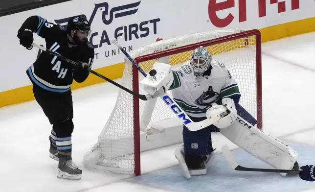 Vancouver Canucks goaltender Thatcher Demko, right, makes a save against Utah Hockey Club center Alexander Kerfoot, left, during the second period of an NHL hockey game Wednesday, Dec. 18, 2024, in Salt Lake City. (AP Photo/Rick Bowmer)