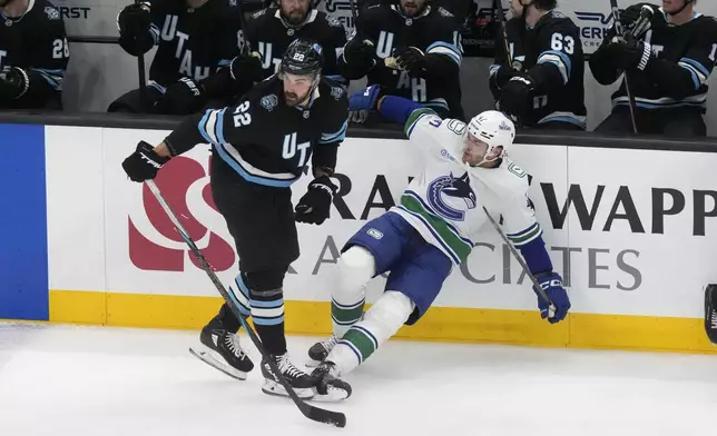 Utah Hockey Club center Jack McBain (22) knocks Vancouver Canucks defenseman Noah Juulsen, right, off his feet during the first period of an NHL hockey game Wednesday, Dec. 18, 2024, in Salt Lake City. (AP Photo/Rick Bowmer)