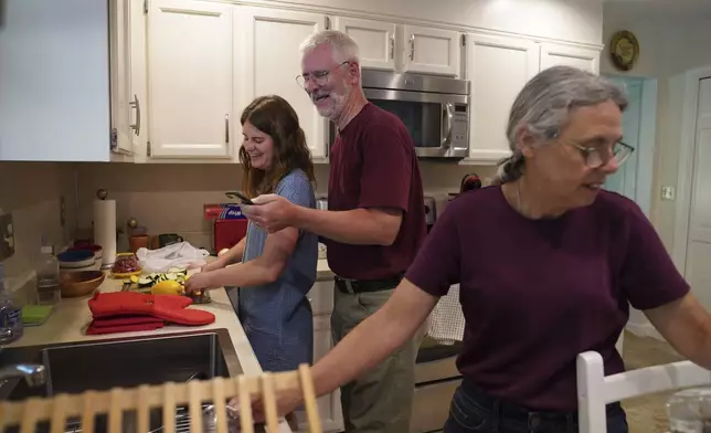 A month before entering the Franciscan Sisters, T.O.R. of Penance of the Sorrowful Mother as a postulant, Zoey Stapleton, left, cooked dinner with her parents Tom and Peggy in Palmyra, Pa., Tuesday, July 2, 2024. (AP Photo/Jessie Wardarski)