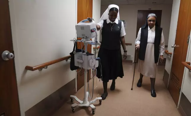 Sister Seyram Mary Adzokpa walks with Sister Mary Laurita in the motherhouse of the Sisters of the Holy Family in New Orleans, Tuesday, June 25, 2024. (AP Photo/Jessie Wardarski) )