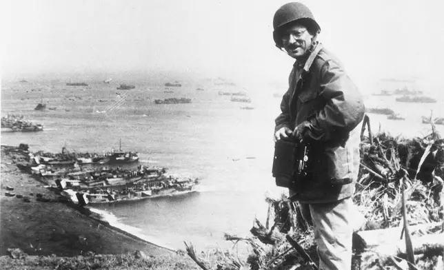 FILE - Joe Rosenthal, an Associated Press photographer, is shown with his camera equipment looking over Iwo Jima, Japanese volcano island during World War II, March,1945. (U.S. Marine Corps via AP, File)