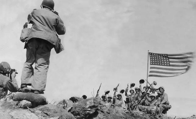 In this image provided by the U.S. Marine Corps, Marines of the 28th Regiment, 5th Division, AP photographer Joe Rosenthal photographs soldiers in front of the U.S. flag atop Mt. Suribachi, Iwo Jima, Japan, Feb. 23, 1945. (USMC/Pfc. Bob Campbell via AP)