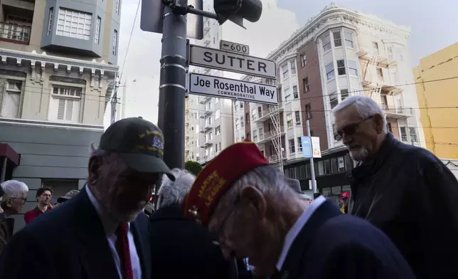 People gather by the street sign Joe Rosenthal Way, that honors the former AP photojournalist who won the Pulitzer Prize for his iconic photo of U.S. Marines raising the flag on the Japanese island of Iwo Jima during WWII, Thursday, Dec. 12, 2024, in San Francisco. (AP Photo/Minh Connors)