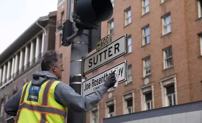 An SFMTA worker installs the Joe Rosenthal Way street sign during the street renaming to honor the former AP photojournalist who won the Pulitzer Prize for his iconic photo of U.S. Marines raising the flag on the Japanese island of Iwo Jima during WWII, Thursday, Dec. 12, 2024, in San Francisco. (AP Photo/Minh Connors)