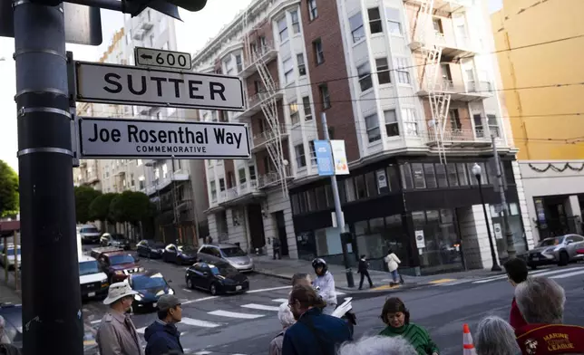 People gather by the street sign Joe Rosenthal Way, that honors the former AP photojournalist who the Pulitzer Prize for his iconic photo of U.S. Marines raising the flag on the Japanese island of Iwo Jima during WWII, Thursday, Dec. 12, 2024, in San Francisco. (AP Photo/Minh Connors)