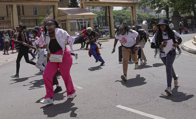 Protesters run from a cloud of tear gas fired by anti-riot police during the march against the rising cases of femicide, in downtown Nairobi, Kenya, Tuesday, Dec. 10, 2024. (AP Photo/Brian Inganga)