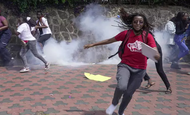 Protesters run from a cloud of tear gas fired by anti-riot police during the march against the rising cases of femicide, in downtown Nairobi, Kenya, Tuesday, Dec. 10, 2024. (AP Photo/Brian Inganga)