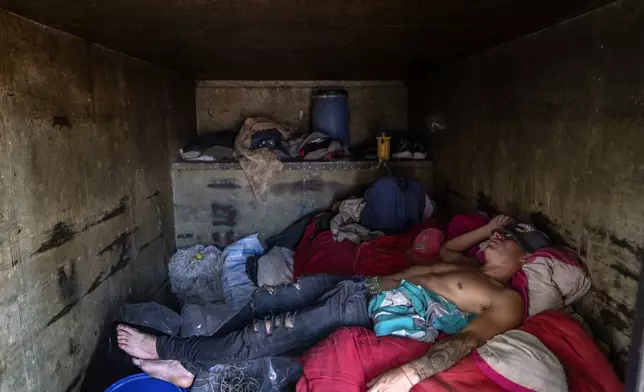Artisanal fisherman Marcelo Munoz nap inside a container used as a base by fishermen before fishing overnight in the Parana River in Villa Gobernador Galvez, Argentina, Wednesday, Dec. 11, 2024. (AP Photo/Rodrigo Abd